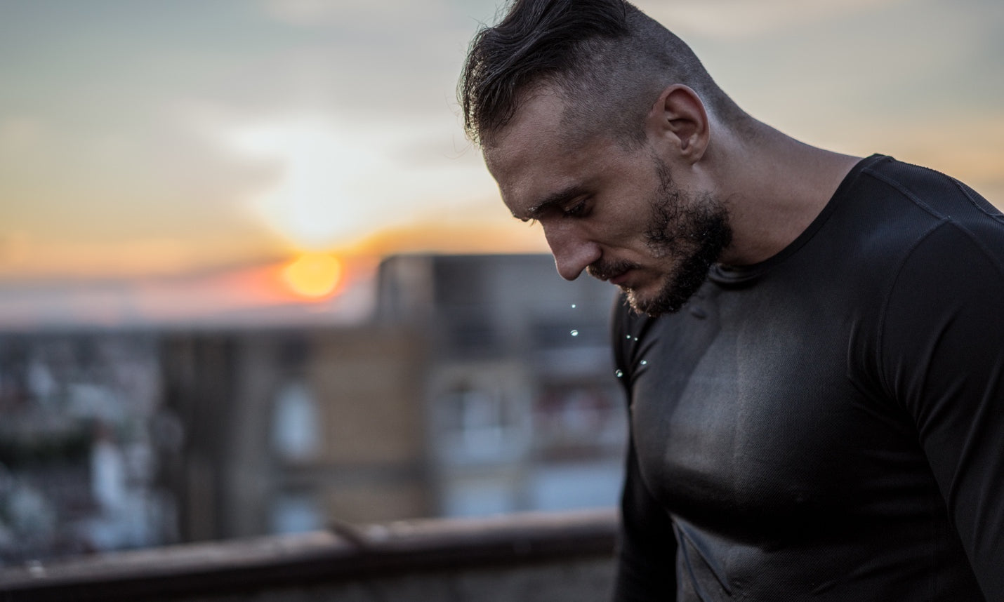 Sweaty male athlete with sunrise in the background